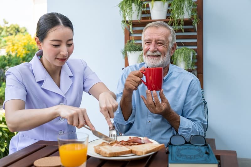 Auxiliaire de vie soccupant du repas dun monsieur âgé