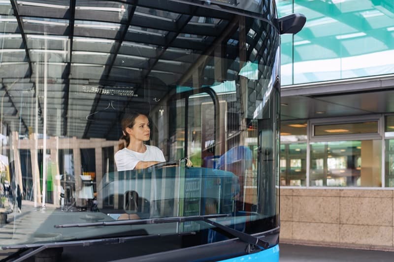 Chauffeur de bus femme au volant dun bus derrière le pare brise