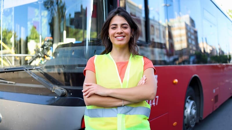 Chauffeur de bus femme souriant devant un bus