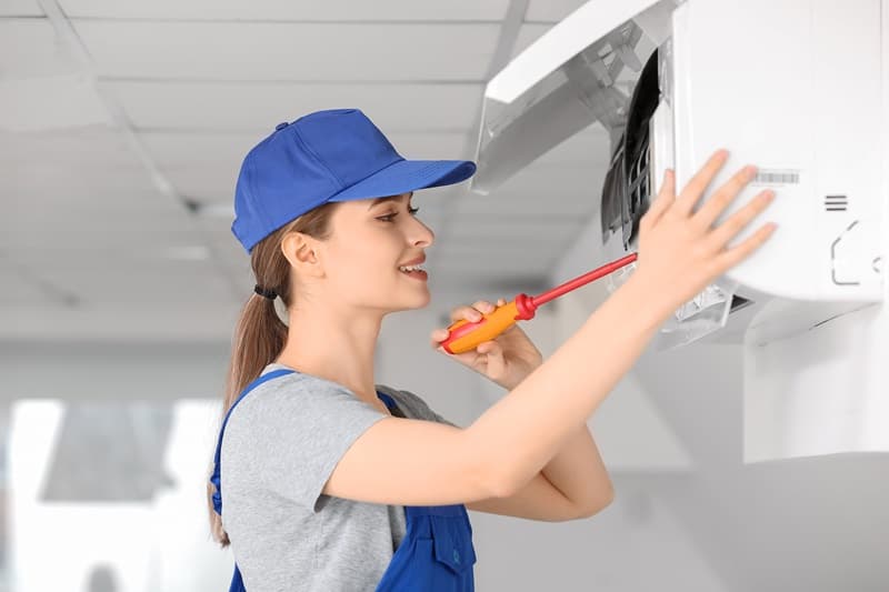 Electricien femme réparant une climatisation