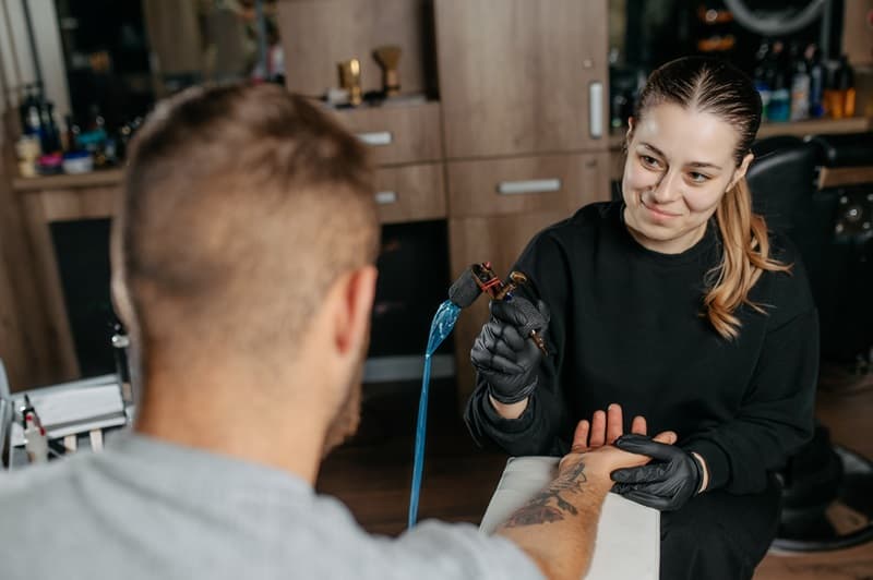 Tatoueuse souriant à son client